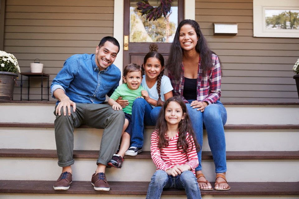 A family sitting on the front steps of the porch smiling because they bundles their pest solutions at Ennis Exterminating.