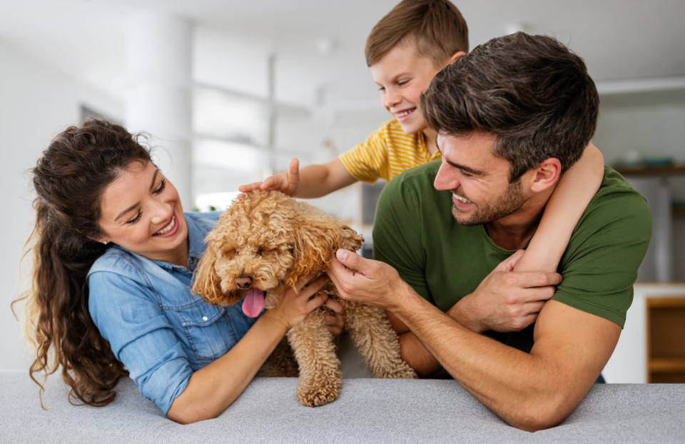 Happy family sitting on the couch amiling with their dog.